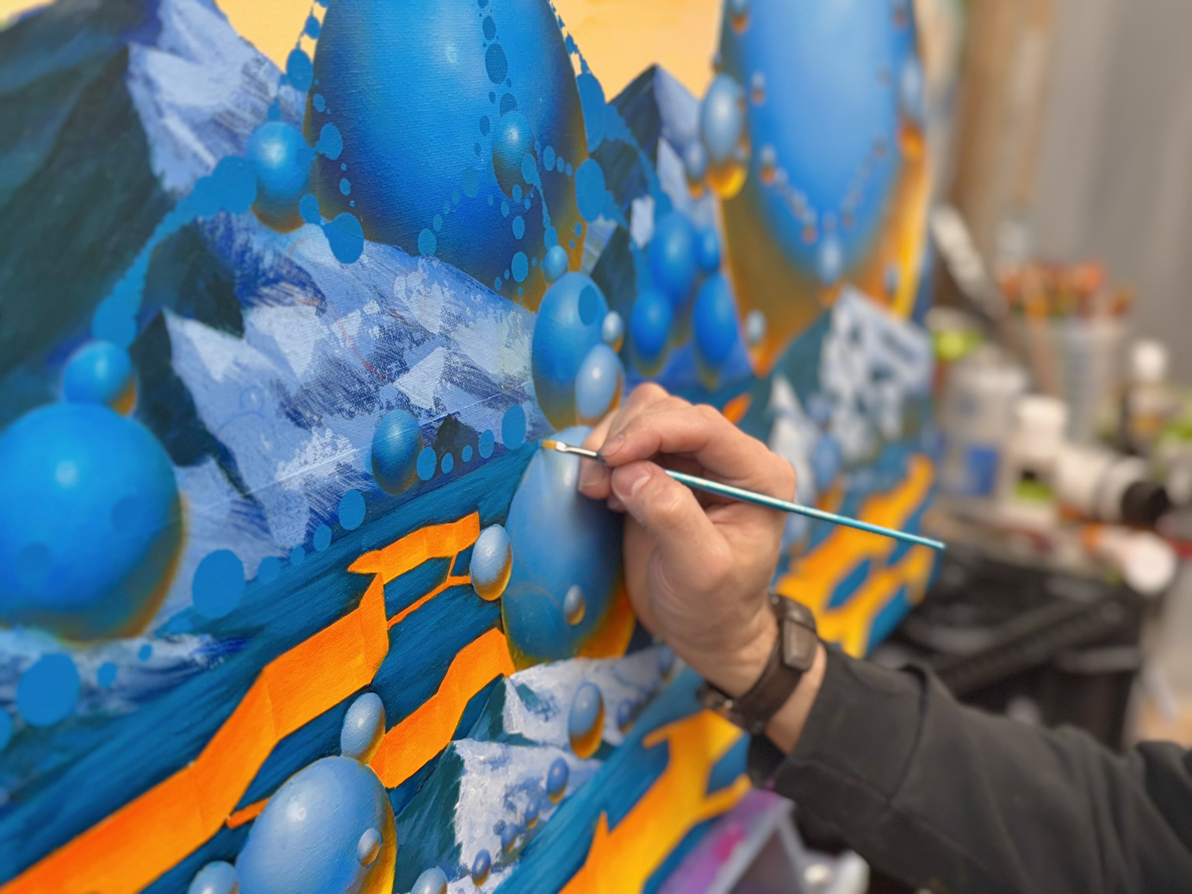Person painting a colorful mural with blue and orange accents
